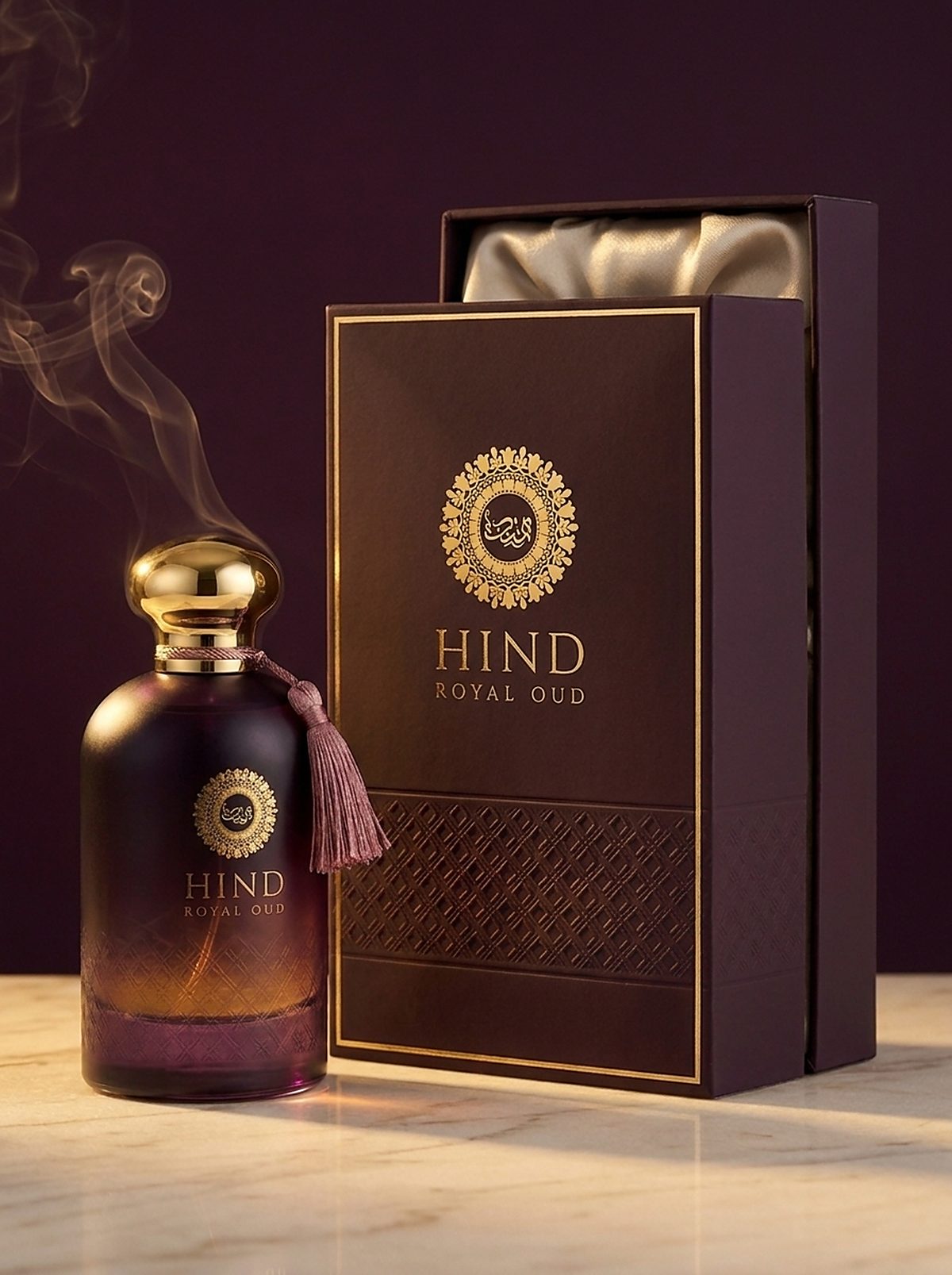 Hind Royal Oud eau de parfum in smoked aubergine glass with a gold cap and rose tassel, beside its gold-framed aubergine coffret lined in champagne satin
